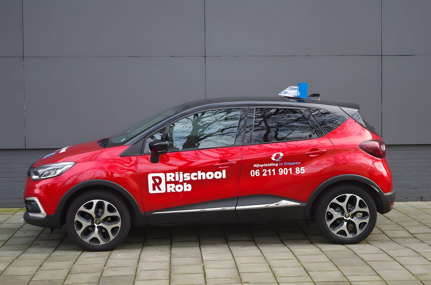 De rode Renault Captur van Rijschool Rob met het witte R-logo
